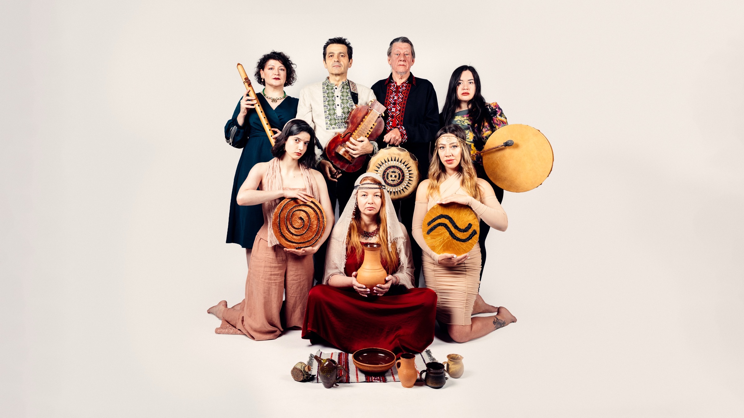 The Trypillian Tarot ensemble holding traditional Ukrainian instruments and Trypillian symbolic vessels, spiral bread and painted ritual discs.